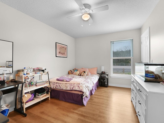 bedroom with a textured ceiling, ceiling fan, and light hardwood / wood-style floors