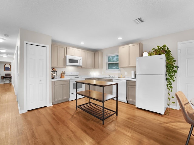 kitchen with white appliances, sink, a textured ceiling, and light wood-type flooring