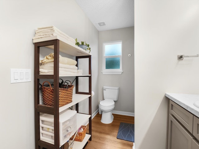 bathroom with hardwood / wood-style flooring, vanity, toilet, and a textured ceiling