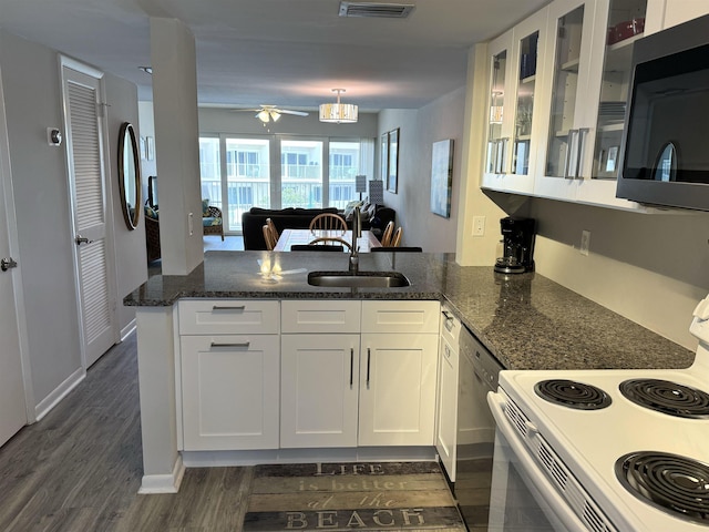 390 A1A Beach Blvd Unit 49, Saint Augustine Beach, FL 32080 - kitchen with stainless steel appliances, a peninsula, a sink, white cabinets, and dark stone counters