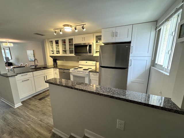 390 A1A Beach Blvd Unit 49, Saint Augustine Beach, FL 32080 - kitchen featuring appliances with stainless steel finishes, a peninsula, dark wood-style flooring, glass insert cabinets, and a sink
