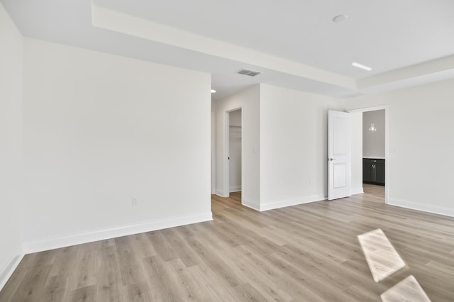 spare room with light wood-type flooring and a tray ceiling