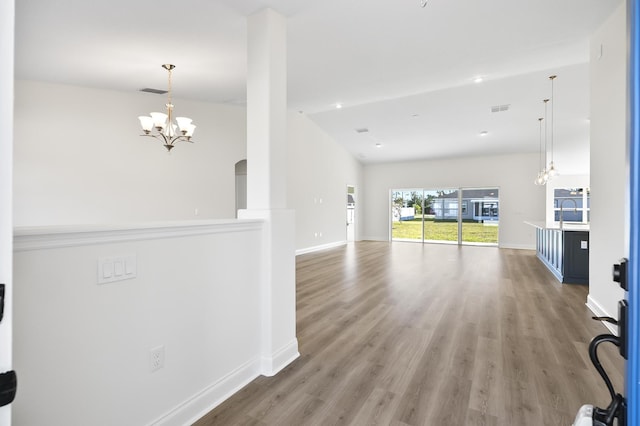 unfurnished living room featuring hardwood / wood-style flooring, a notable chandelier, lofted ceiling, and sink