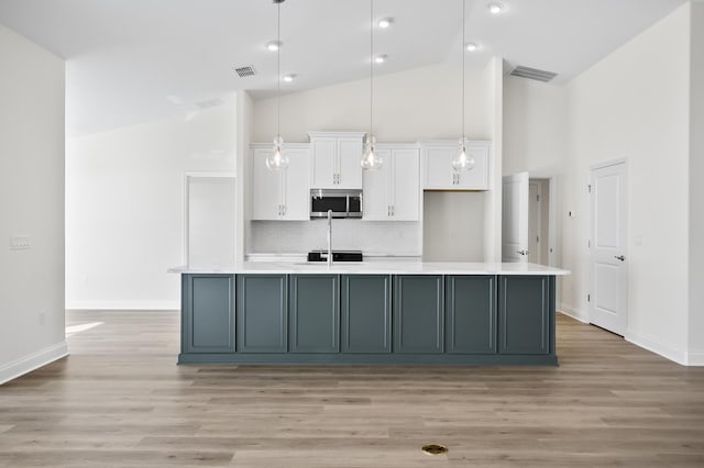 kitchen with backsplash, decorative light fixtures, white cabinetry, and a spacious island