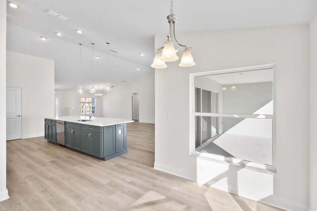 kitchen featuring dishwasher, sink, lofted ceiling, decorative light fixtures, and a center island with sink