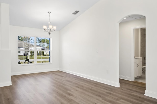 spare room featuring dark hardwood / wood-style flooring and an inviting chandelier