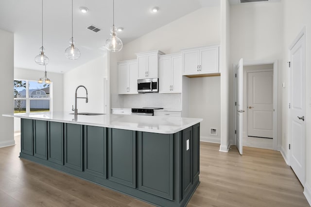 kitchen featuring a spacious island, sink, decorative light fixtures, white cabinetry, and stainless steel appliances