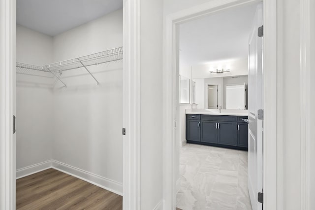 walk in closet with sink and light wood-type flooring