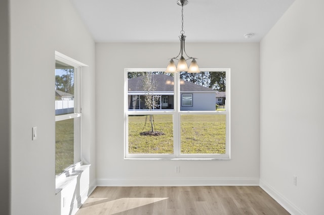 unfurnished dining area with light hardwood / wood-style floors and a notable chandelier