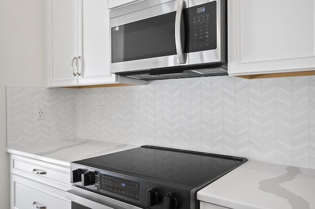 kitchen featuring white cabinetry, stove, and light stone counters