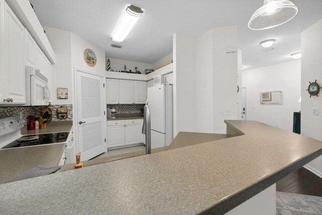 104 Laurel Wood Way Unit 202, Saint Augustine, FL 32086 - kitchen with white appliances, backsplash, white cabinets, a peninsula, and light wood-style floors