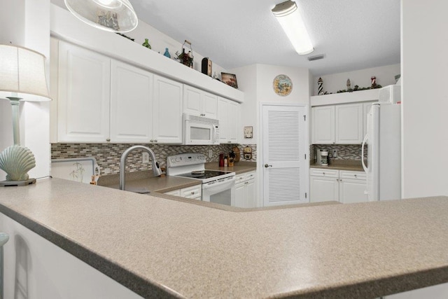 104 Laurel Wood Way Unit 202, Saint Augustine, FL 32086 - kitchen with white appliances, tasteful backsplash, white cabinets, light countertops, and a peninsula