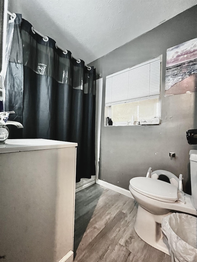 bathroom featuring toilet, curtained shower, wood finished floors, and baseboards