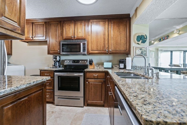 4670 A1A S Unit 1309, Saint Augustine, FL 32080 - kitchen with a textured ceiling, appliances with stainless steel finishes, a sink, light stone counters, and light tile patterned floors