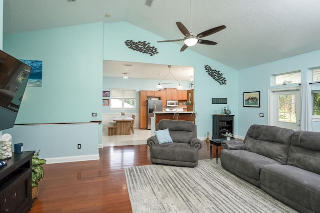 living room featuring ceiling fan, light hardwood / wood-style flooring, a healthy amount of sunlight, and lofted ceiling