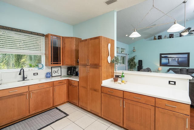 kitchen with pendant lighting, lofted ceiling, sink, light tile patterned floors, and kitchen peninsula