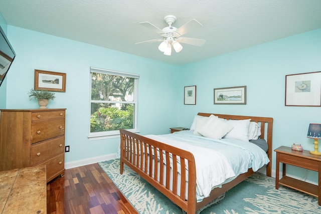 bedroom with ceiling fan, dark wood-type flooring, and a textured ceiling