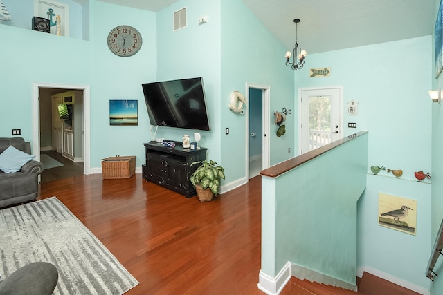 living room featuring a chandelier, high vaulted ceiling, and dark wood-type flooring