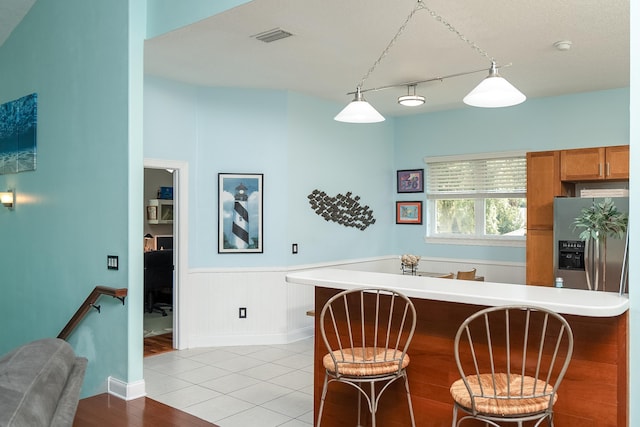 kitchen with pendant lighting, track lighting, light hardwood / wood-style flooring, a textured ceiling, and stainless steel fridge with ice dispenser