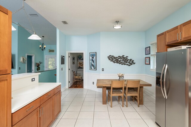 kitchen featuring stainless steel refrigerator with ice dispenser, a textured ceiling, pendant lighting, and light tile patterned flooring