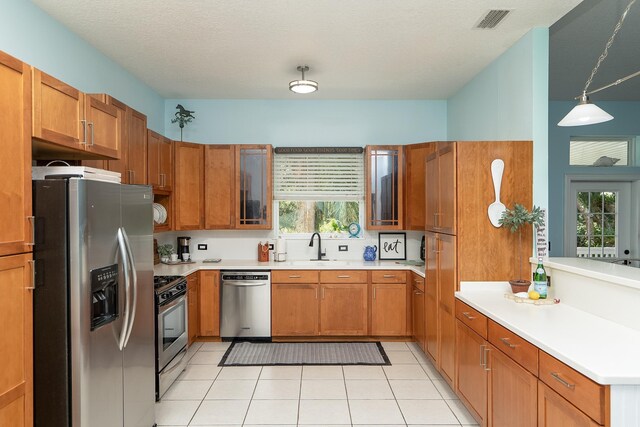 kitchen with appliances with stainless steel finishes, a textured ceiling, decorative light fixtures, and a healthy amount of sunlight