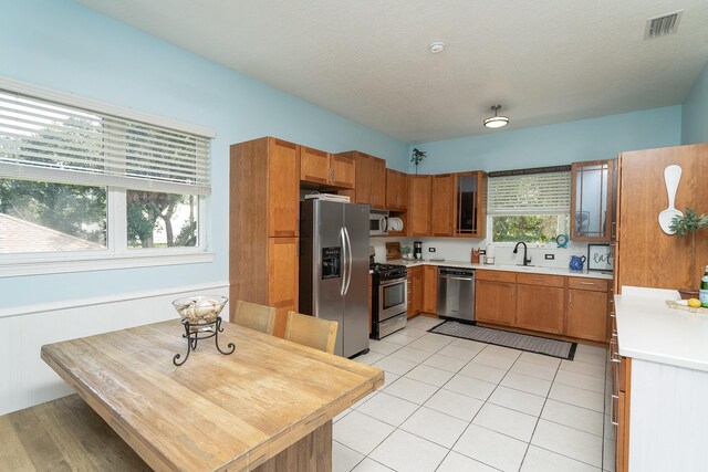 kitchen with sink, light tile patterned floors, a textured ceiling, and appliances with stainless steel finishes