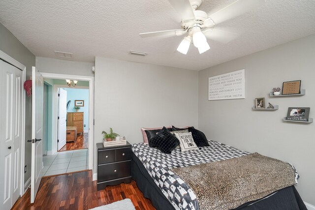 bedroom featuring dark hardwood / wood-style floors, ceiling fan, a textured ceiling, and a closet