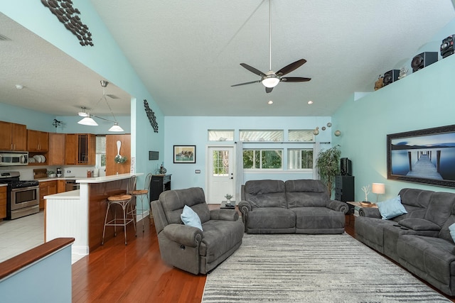 living room with a textured ceiling, dark hardwood / wood-style floors, high vaulted ceiling, and ceiling fan