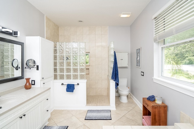 bathroom featuring tile patterned flooring, vanity, toilet, and tiled shower