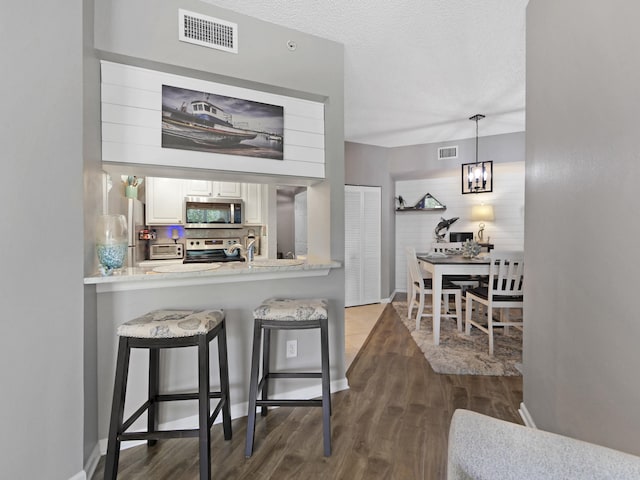 bar featuring stainless steel appliances, visible vents, dark wood-style floors, and tasteful backsplash