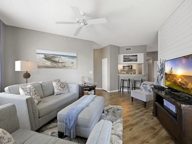 living room with visible vents, wood finished floors, a textured ceiling, and ceiling fan