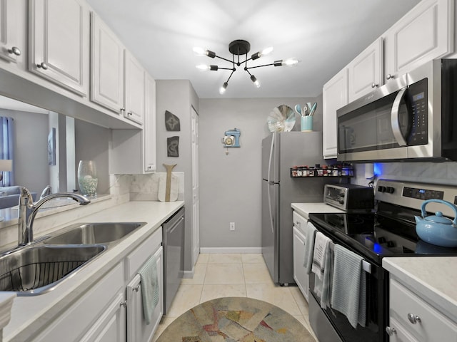 kitchen with white cabinets, stainless steel appliances, light countertops, a sink, and a notable chandelier