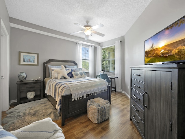 bedroom with a ceiling fan, wood finished floors, and a textured ceiling