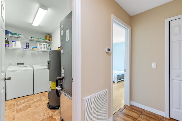 clothes washing area featuring independent washer and dryer and water heater