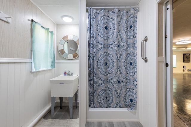 bathroom with a shower with shower curtain, wood walls, and hardwood / wood-style floors