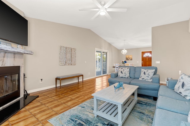 tiled living room featuring a tiled fireplace, ceiling fan with notable chandelier, and lofted ceiling