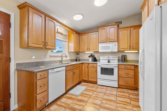 kitchen with white appliances, sink, vaulted ceiling, light tile patterned floors, and light brown cabinetry