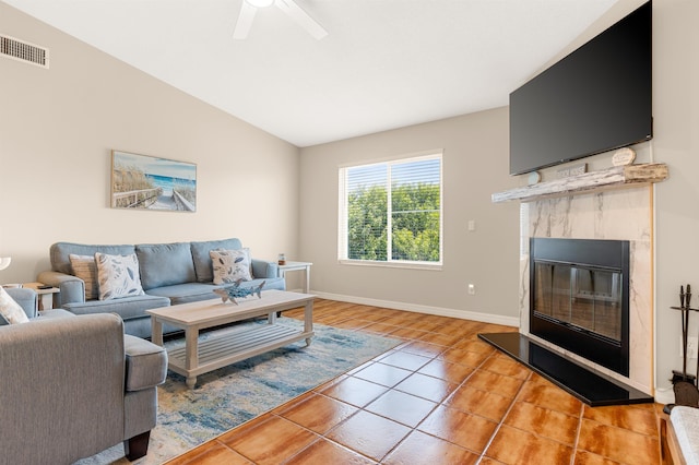 tiled living room featuring ceiling fan, lofted ceiling, and a tiled fireplace