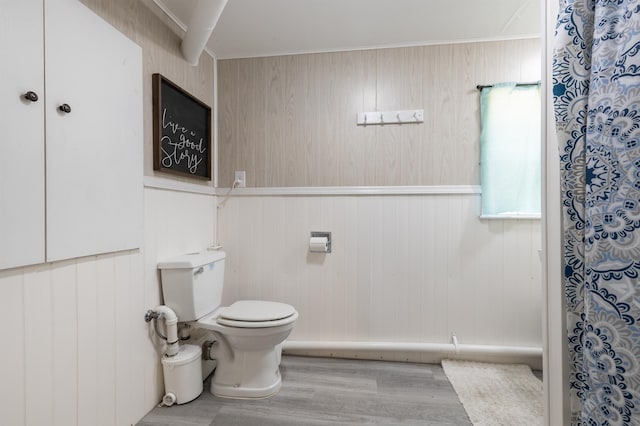 bathroom with toilet, wood-type flooring, and wooden walls