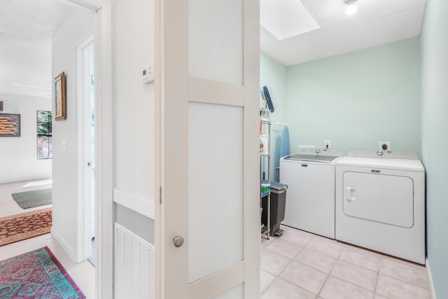 laundry area with laundry area, a skylight, light tile patterned flooring, and independent washer and dryer