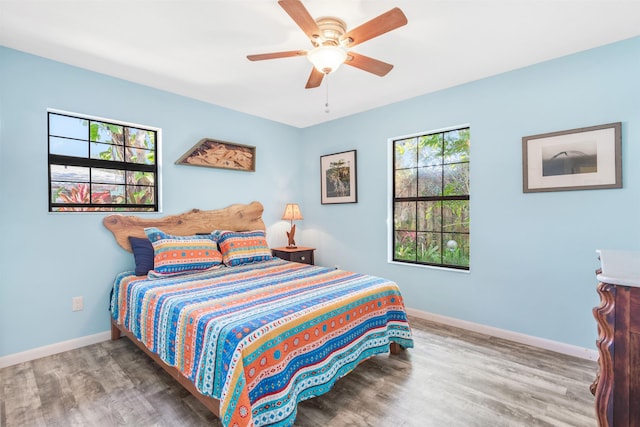 bedroom featuring ceiling fan, baseboards, and wood finished floors