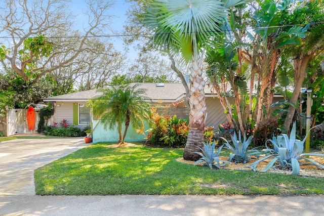 view of front facade with a front yard, concrete driveway, and fence