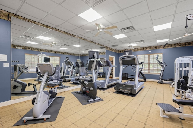 gym featuring a wealth of natural light, ceiling fan, and a drop ceiling