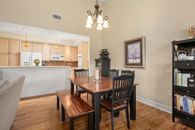 dining area with light hardwood / wood-style flooring and a chandelier