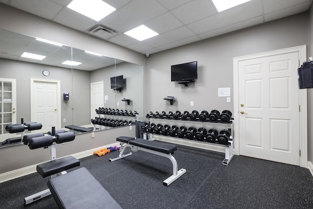 exercise room featuring a paneled ceiling, baseboards, and visible vents