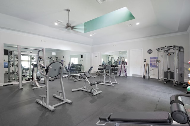 gym with baseboards, visible vents, a ceiling fan, ornamental molding, and a tray ceiling