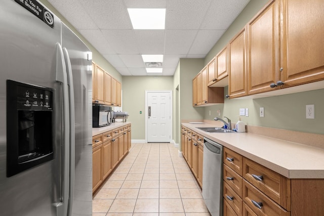 kitchen featuring light tile patterned floors, light countertops, appliances with stainless steel finishes, and a sink