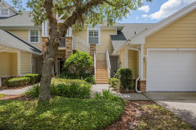 view of front of property with a shingled roof, concrete driveway, stairway, and a garage