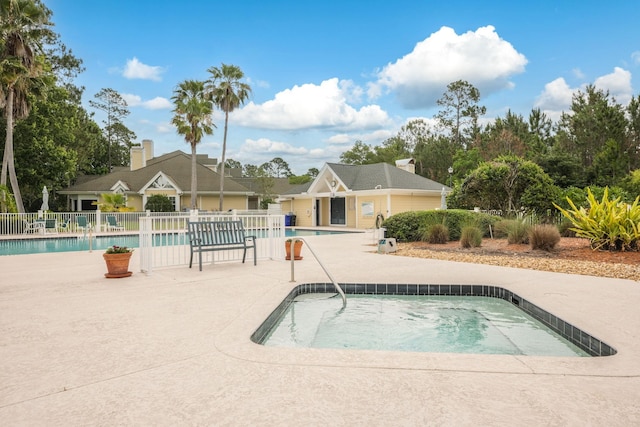 community pool with a patio and fence