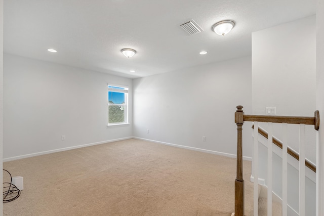 carpeted empty room with baseboards, visible vents, and recessed lighting